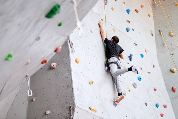 istock man climbing on artificial boulders wall indoor, rear view 1158641088