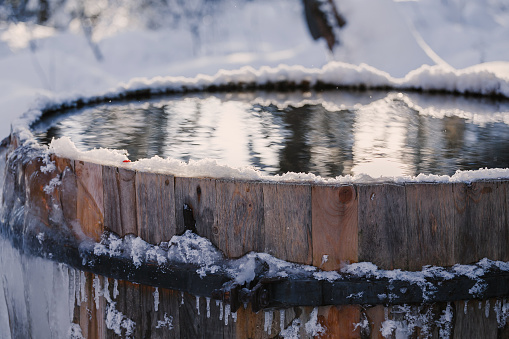 Big barrel with clean cold water outdoors in forest covered with snow. Winter swimming concept