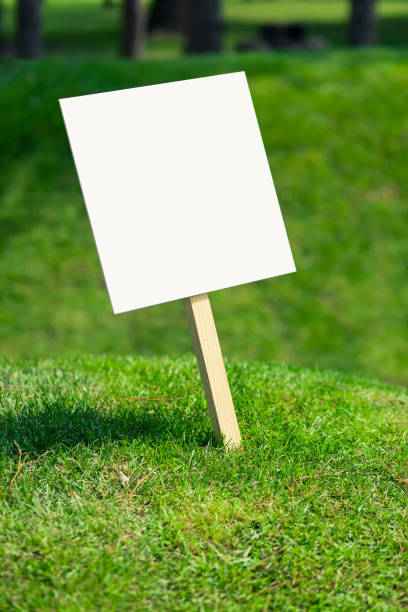 istock Empty white sign board on a small hill with freshly cut green grass and meadow in the background 1158643333
