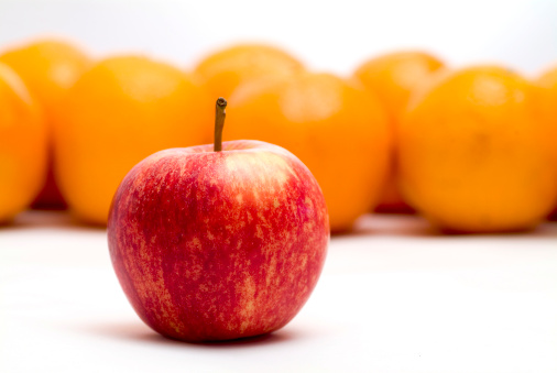 Oranges behind a red apple