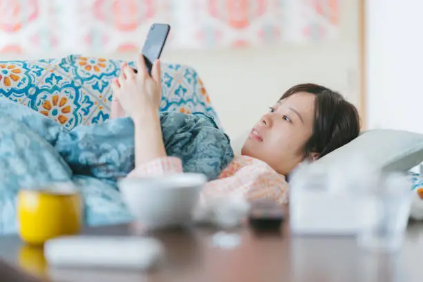 Photo of Woman feeling sick at home checking smart phone