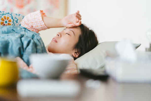 女性は気分が悪く、自宅のソファで寝ている - 不眠症 ストックフォトと画像