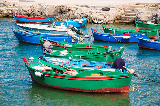Beautiful old colored fishing wooden boats on the water with rocks on background