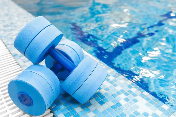 Photo of dumbbells equipment for aqua aerobics sport near swimming pool