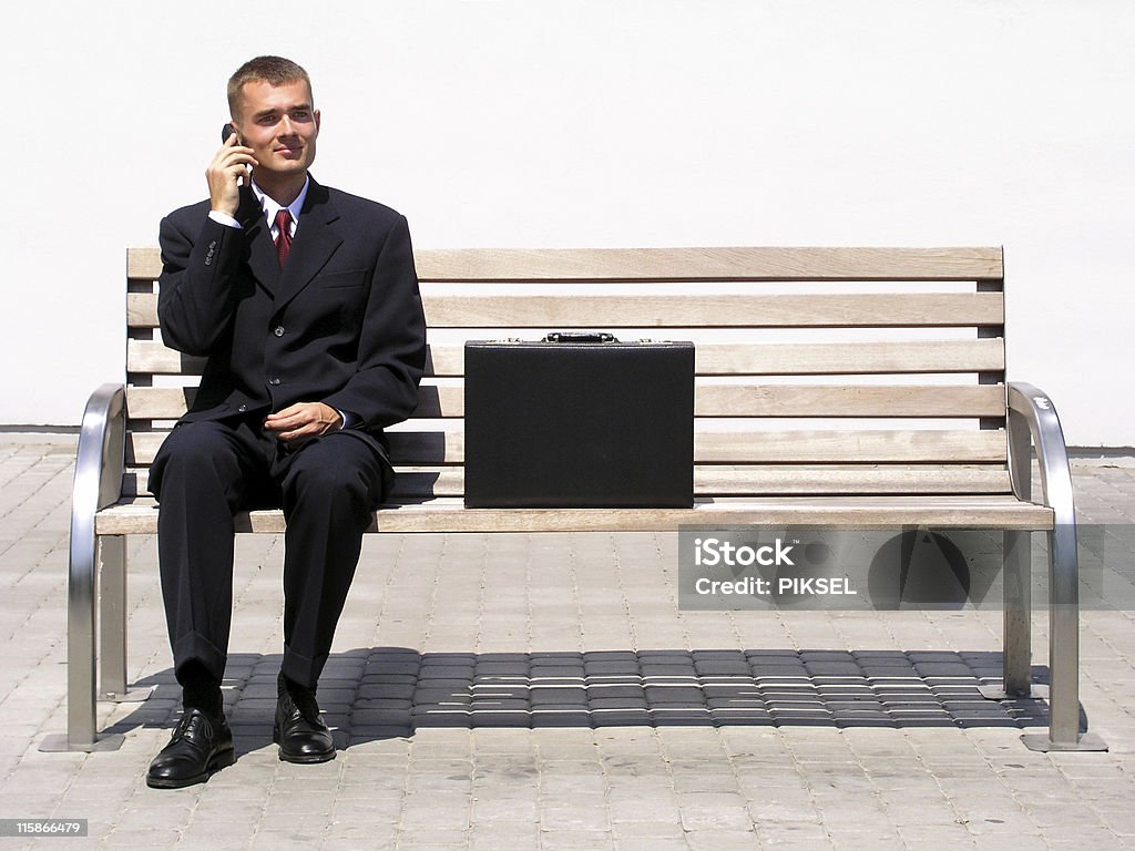 Businessman using a mobile phone sitting on bench http://www.edkafelek.com/businesspeople.jpg Bench Stock Photo