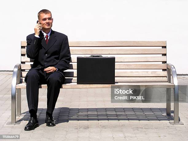 Businessman Using A Mobile Phone Sitting On Bench Stock Photo - Download Image Now - Bench, Businessman, Sitting