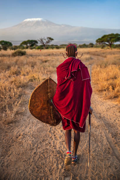 Warrior from Maasai tribe, Mount Kilimanjaro on background, Kenya, Africa African warrior from Maasai tribe, Mount Kilimanjaro on the background, central Kenya, Africa. Maasai tribe inhabiting southern Kenya and northern Tanzania, and they are related to the Samburu. masai stock pictures, royalty-free photos & images