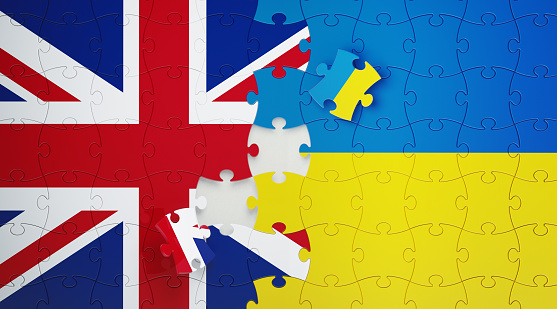 Jigsaw puzzle pieces textured with Ukrainian and United Kingdom flags. Horizontal composition with copy space and selective focus. Solution concept.