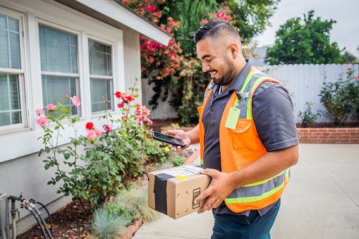 A young hispanic man delivering packages in a residential neighborhood.