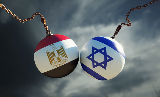 Wrecking balls textured with Egyptian and Israeli flags over dark stormy sky. Horizontal composition with copy space and selective focus. Dispute concept.