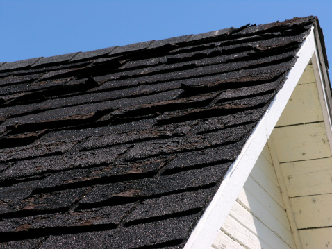 Roof in need of repair. The asphalt shingles are badly worn and should be replaced.