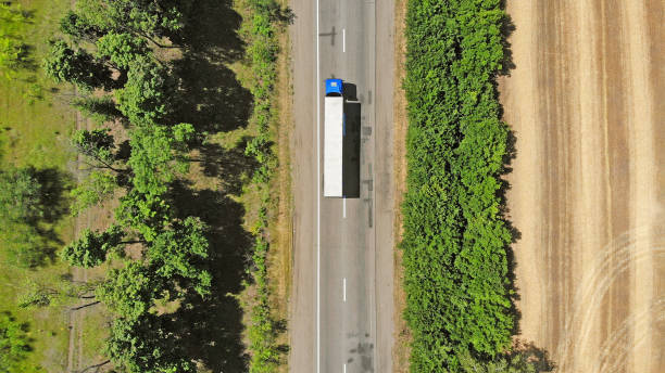 aérea. caminhão azul em uma estrada entre campos. fundo da logística do transporte. - flatbed truck truck truck driver heavy - fotografias e filmes do acervo