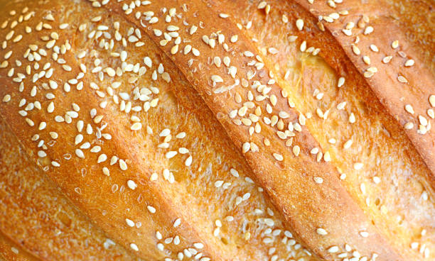 istock Warm and fragrant crust of sesame bread close-up. 1158674424