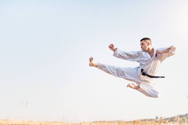 giovane artista marziale che pratica calci volanti in natura. - karate foto e immagini stock