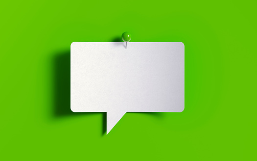 White post it note pinned with a green push pin on green background.  Horizontal composition with copy space.