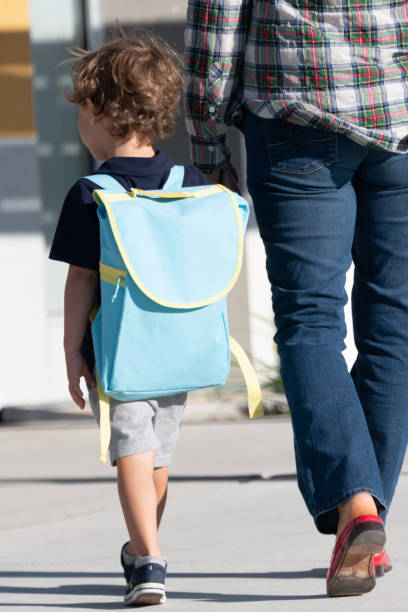 学校に戻って、小さな男の子は、彼のお母さんと一緒に学校の最初の日に歩いて - little boys preschooler back to school backpack ストックフォトと画像