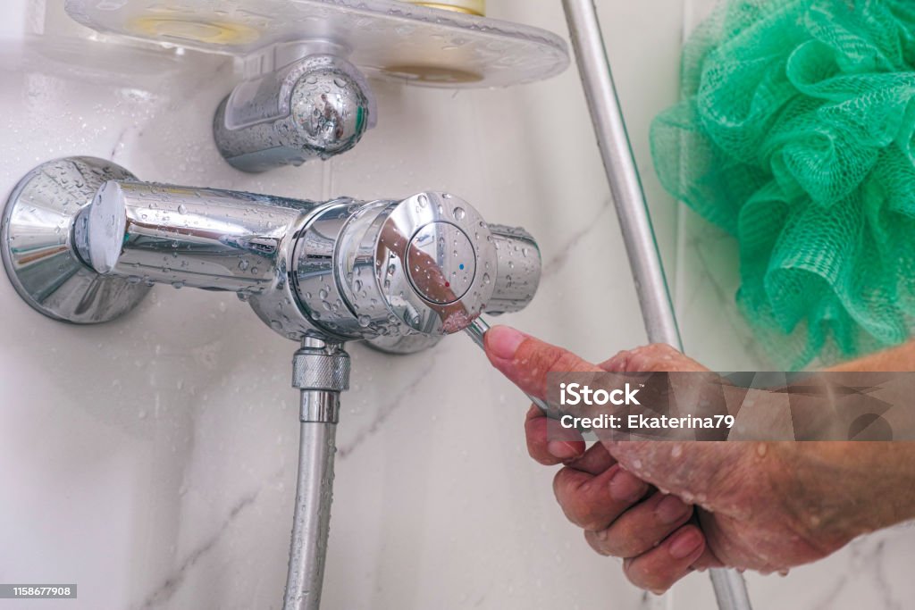 Person hand using faucet in the shower. Close up Shower Stock Photo