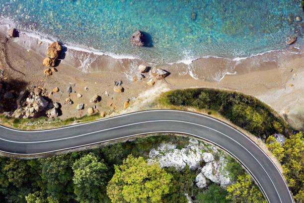 strada sul mare che si avvicina a una spiaggia, vista dall'alto - asphalt beauty in nature nature scenics foto e immagini stock