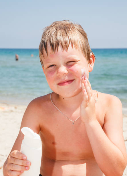 istock Boy applying sunscreen on his chest at a beach 1158680318