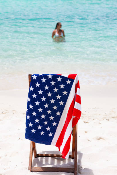 amerikanische flagge handtuch auf stuhl mit frau tropischen strand in unberührten inseln - women sarong beach white stock-fotos und bilder