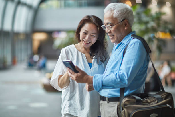 istock Senior Asian Couple Using Smart Phone in Transportation Hub 1158683479
