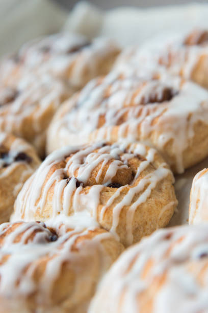 Close-up of freshly baked vegan cinnamon rolls drizzled with vanilla frosting
