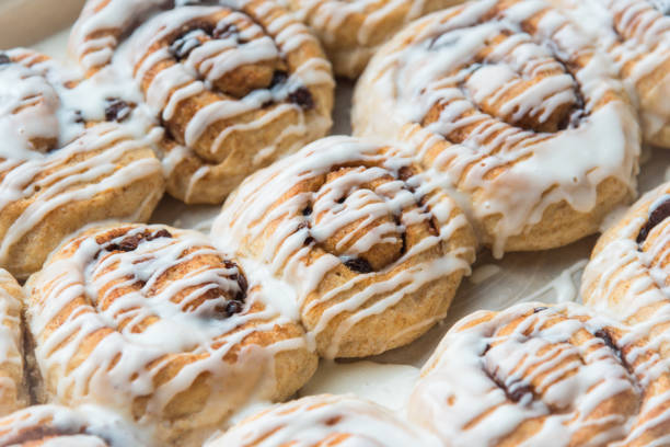 Pan of vegan whole-wheat homemade cinnamon raisin rolls drizzled with vanilla frosting
