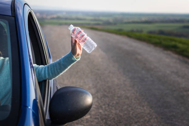 istock Do not pollute environment with plastic ! Driver hand holding plastic bottle from car window. 1158683948
