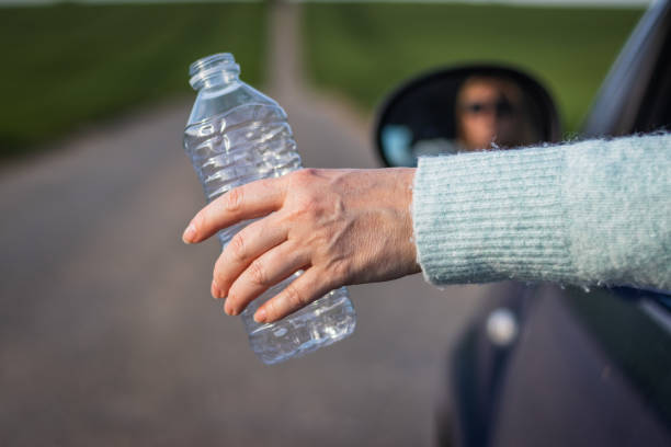 istock Do not pollute environment with plastic ! Driver hand holding plastic bottle from car window. 1158684054