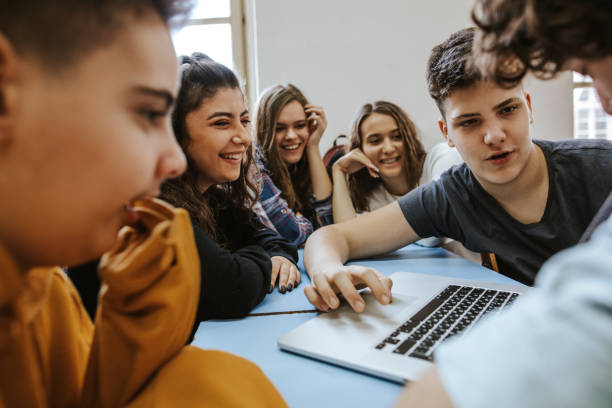 istock Group of teenagers talking and smiling while they are using laptop 1158686742