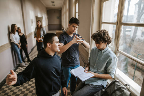 Boys bullying classmate in the school corridor while girls watching Boys bullying classmate in the school corridor while girls watching incidental people stock pictures, royalty-free photos & images