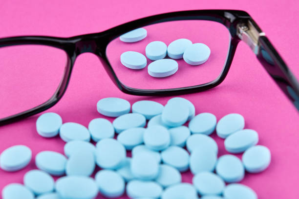 istock Glasses and blue pills on pink background. Medicine 1158686936