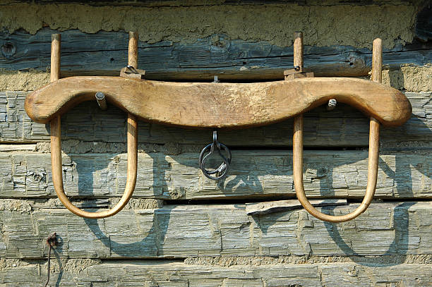 ox yoke hanging on wooden wall Ox yoke against rough hewn log wall. Living History Farms, Urbandale (suburb of Des Moines), Iowa. yoke stock pictures, royalty-free photos & images