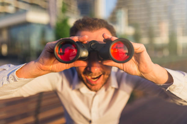 Close up of cheerful businessman with binoculars outdoors.