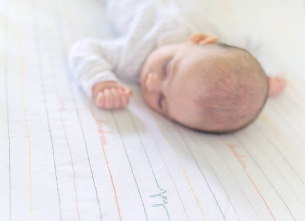 Darling 3 month old newborn baby sleeps in a peaceful neutral nursery, peaceful and quiet baby asleep and resting. The word joy