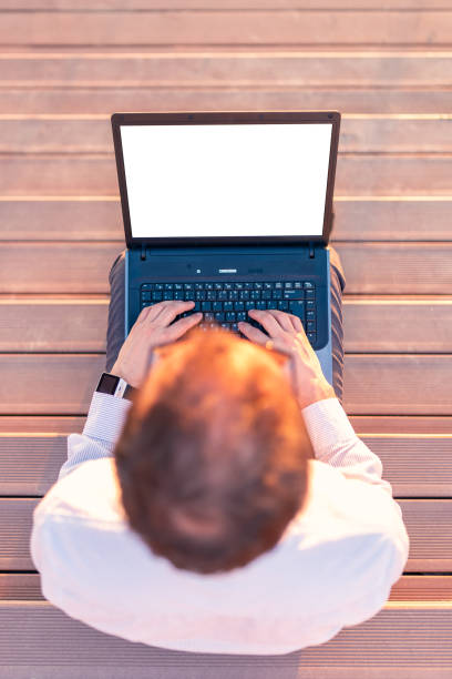 high angle view of businessman sitting on stairs and using blank screen laptop outdoors. - surfing wireless vertical outdoors lifestyles imagens e fotografias de stock