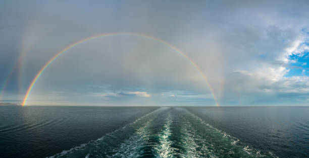 Madeira seascapes. Close-up view of beautiful rainbow that arches over the vast ocean waves beneath cloudy sky, creating scenic and serene atmosphere. Dreamlike