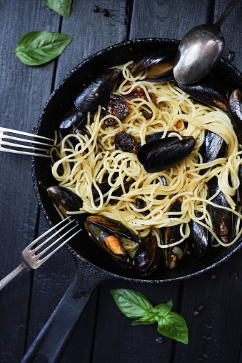 Pasta with shellfish. Spaghetti allo scoglio rustic style in cast iron pan top view