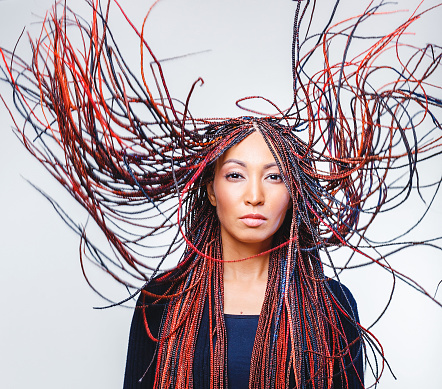 Conceptual studio shot of a modern creative woman with colorful flying braided dreads