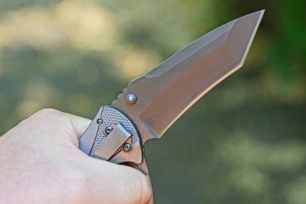 istock black folding knife in his hand on a gray background 1158695018