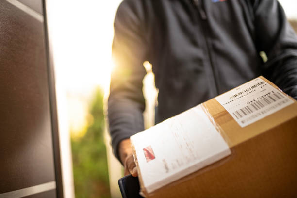 Courier holding cardboard box for delivery Close up of an unrecognisable courier holding cardboard box prepared for home delivery. delivery person stock pictures, royalty-free photos & images