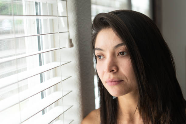 istock Concerned hispanic young woman looking through a window 1158699750