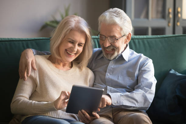 cheerful elderly spouses having fun using digital tablet - digital tablet women enjoyment happiness imagens e fotografias de stock