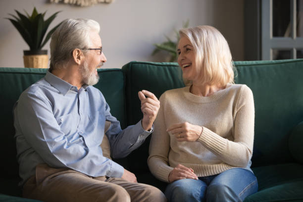 istock Cheerful elderly spouses sitting on couch chatting feel happy 1158702056