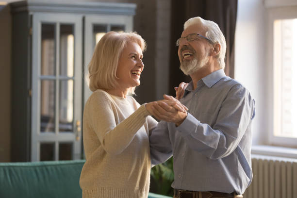 a dança idosa alegre dos cônjuges aprecia o tempo livre em casa - senior adult family cheerful couple - fotografias e filmes do acervo