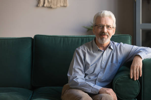 istock Single handsome elderly man sitting on couch looking at camera 1158702141