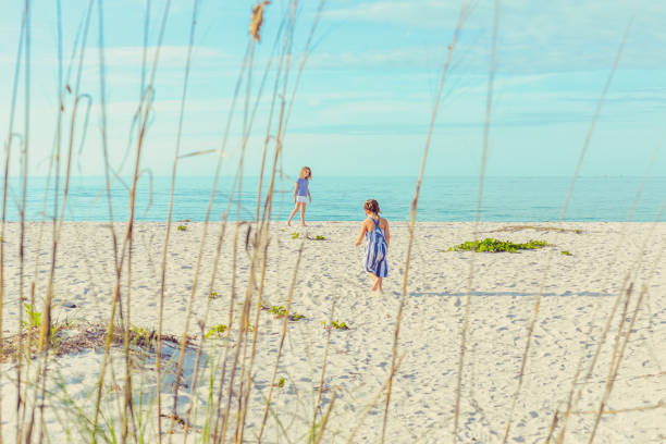 istock Two girls walking on the beach in an idyllic oceanfront area 1158702413