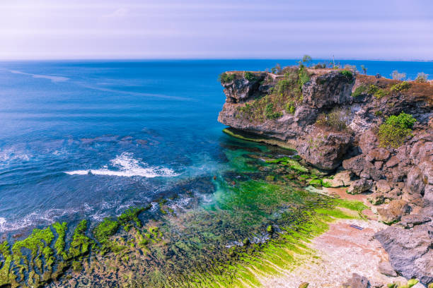 widok z lotu ptaka na chropowate i wyblakłe klify na wybrzeżu na plaży balangan z zielonym mchem i błękitnym niebem w rejonie kuta na bali, indonezja - kuta beach zdjęcia i obrazy z banku zdjęć