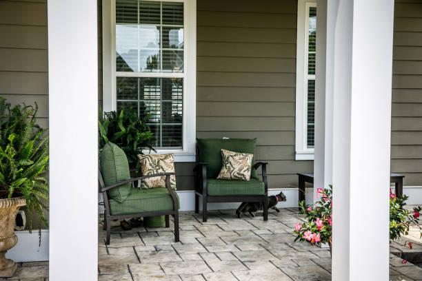Front porch of a home in the suburbs Front porch of a home in the suburbs. The home has columns and siding on the porch has furniture and plants and flowers and a black cat. front porch stock pictures, royalty-free photos & images