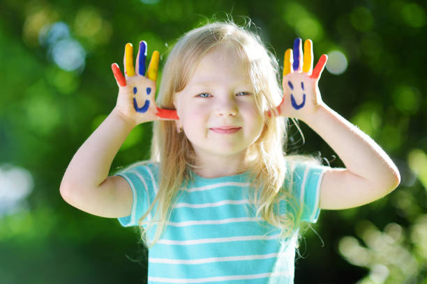 menina adorável com suas mãos pintadas que têm o divertimento ao ar livre - outdoors looking at camera little girls child - fotografias e filmes do acervo